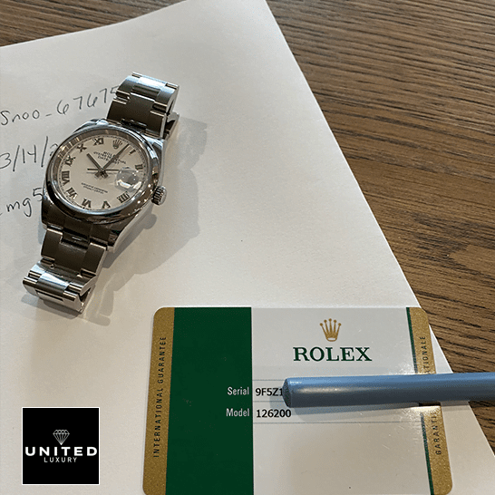 Rolex Datejust 126200-0008 White Dial Swiss Super Clone rolex datejust 126200 0008 replica stainless Rolex datejust Replica watch and warranty card on the table